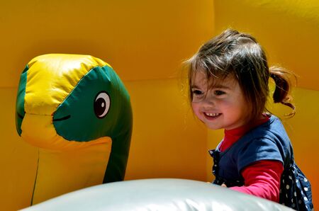 Happy child girl jumps on a children's bouncy castle inflatable jumper playground.の写真素材
