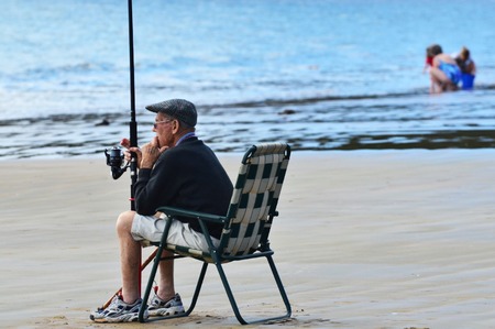 A very old man fishing a the beach.の写真素材