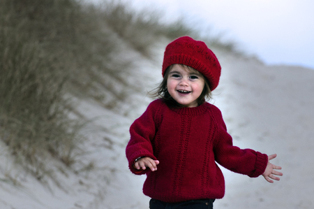 Baby girl play at the beach during the winter.の写真素材