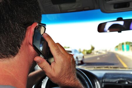 Concept photo of a male driver speaks on a mobile phone while driving.の写真素材