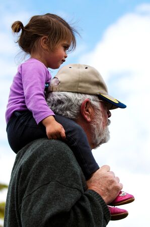 Little girl sitting on here grandfather'd shoulders.の写真素材