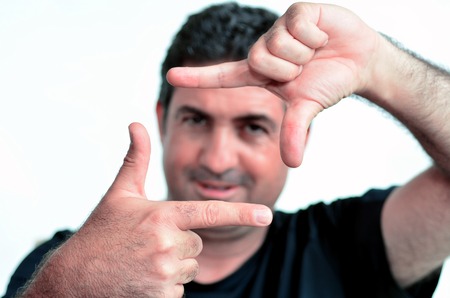 Happy one young mature man only creating frame with fingers.Copy space on white background. real people. Concept photo of cool, creative, confident,  aspirations, manly, man.の写真素材