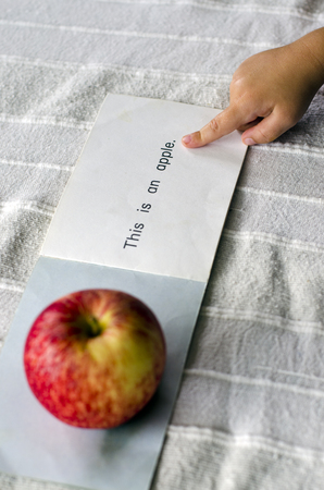 A hand of a preschooler learning to read the English word, Apple.の写真素材