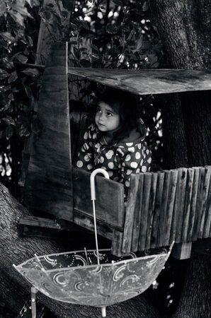 Little girl get shelter in a treehouse during the rain.の写真素材