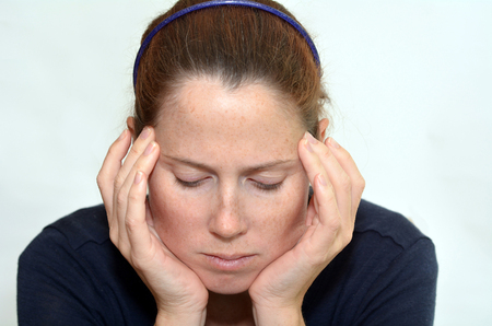 Young woman with headache holding her hands against the head isloated against white background with copy space. Real people concept photo of woman stress, headache , depression, depressed, unhappy.の写真素材