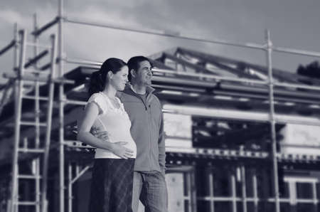 Young couple hugging outside their new home. Concept buying a new house. (BW)の写真素材
