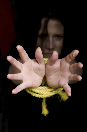 Missing kidnapped, abused, hostage, victim woman with hands tied up with rope in emotional stress...