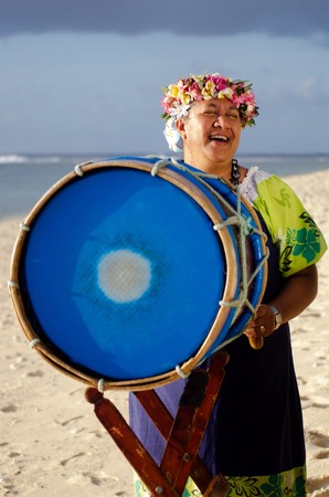 Portrait of mature Polynesian Pacific islanders woman sing and plays Tahitian Music with drum on tropical beach. (Photo have MR)の写真素材