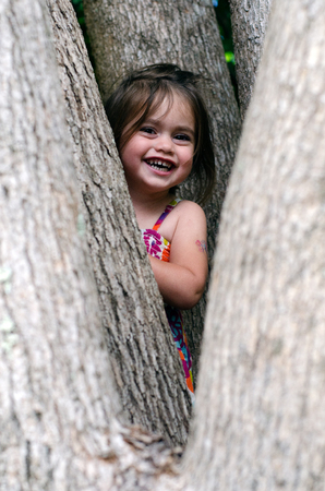 Cute little girl is playing hide and seek outdoors.の写真素材
