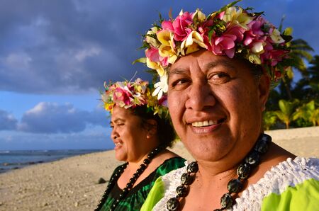 Portrait of two happy smily mature Polynesian Pacific islanders women on tropical beach with palm trees in the background.の写真素材