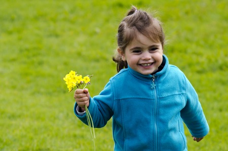 Happy little girl holds yellow flowers outdoor. (copy space)の写真素材