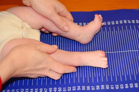 Hands of pediatrician nurse checks the height of Infant baby on ruler measure during body development and body height examination.の写真素材