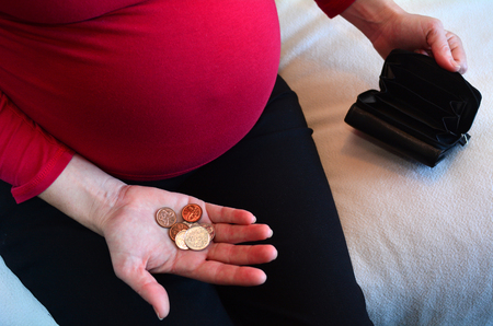 Pregnant woman with small money and empty wallet during pregnancy.Concept photo of pregnancy, pregnant woman lifestyle, money and finance. copy spaceの写真素材