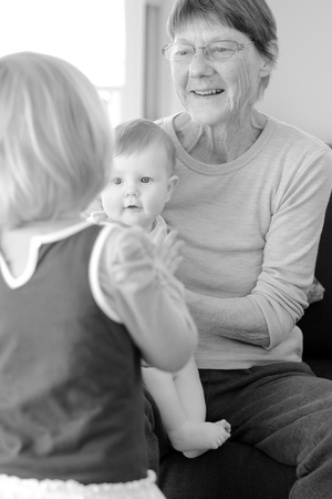 Happy grandmother play with her grandchildren at home. Concept photo of newborn, baby, grandmother,...