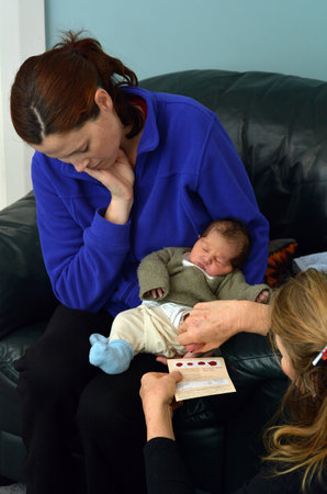 AUCKLAND - JUNE 09 2014:Midwife take blood sample from a newborn during metabolic screening test.Newborn screening samples are collected from the infant between 24 hours and 7 days after birth.のeditorial素材
