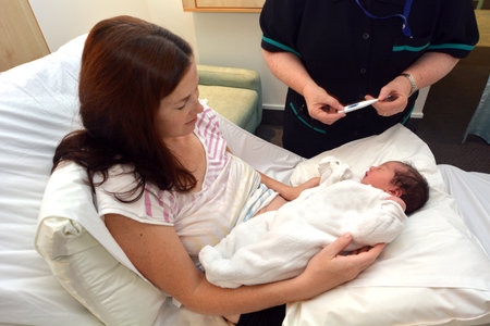 AUCKLAND - JUNE 10 2014: A Midwife checking newborn temperature.A healthy person's average  body temperature is 98.6Â°F (37Â°C)のeditorial素材
