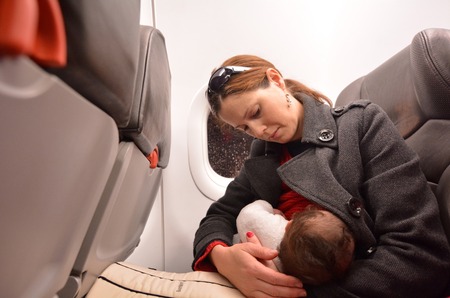 Mother breastfeeding her newborn baby during flight.Concept photo of air travel with baby.の写真素材