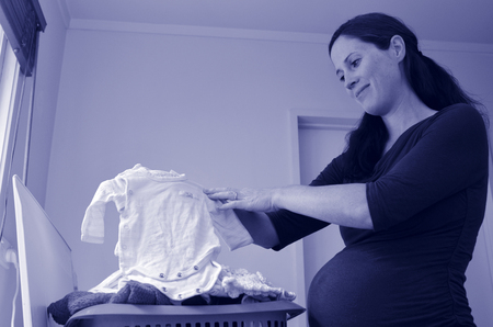 Happy pregnant housewife woman doing housework , washing newborn baby clothes, during pregnancy.Concept photo of pregnancy, pregnant woman lifestyle and health care. copyspace (BW)の写真素材