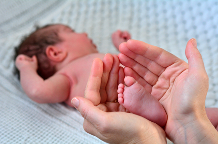Hand of a young mother touch her newborn baby foot (3 week old).copyspaceの写真素材