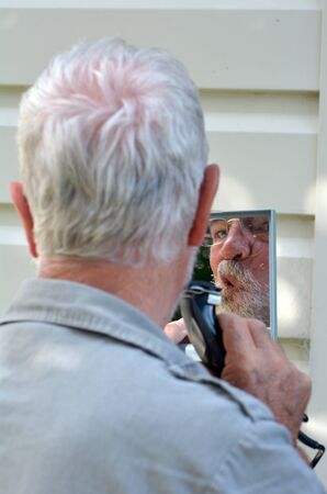 Mature man trim his beard outdoor. concept photo of man body careの写真素材