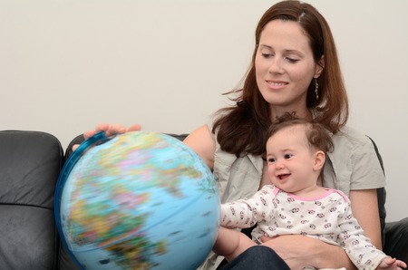 Mother and baby (girl age 06 months) search and examining the Globe  at home. Concept photo travel...