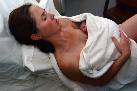 Mother rest with her newborn baby in bed immediately after a natural water birth labour. Concept...