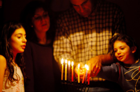A family is lighting a candle for the Jewish holiday of Hanukkah.の写真素材
