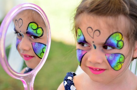 little girl getting with face  looks at the mirror. Focus on mirror reflectionの写真素材
