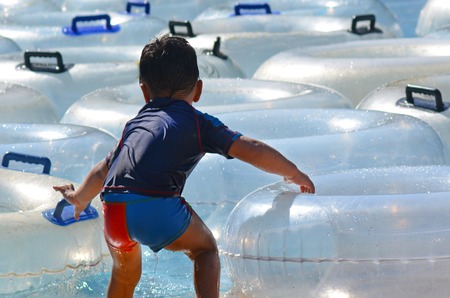 Child (Boy age 2) play with Inflatable clear inner tubes floating in clear blue watersの写真素材