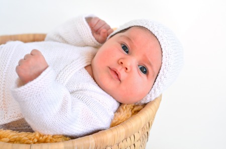 Baby girl lying down in basket in winter day on white background copy space.の写真素材
