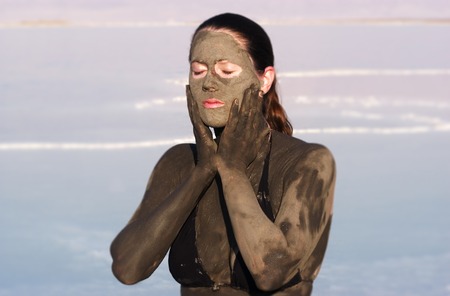 A young woman in a bathing suit is enjoying the natural mineral mud sourced from the dead Sea, Israel.の写真素材