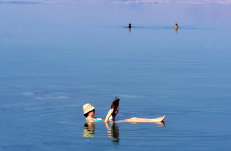 A young woman floating while reading a magazine at the Dead Sea, Israel.の写真素材