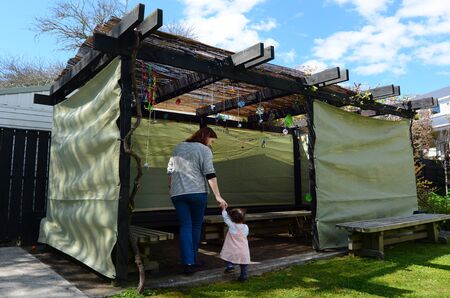 Jewish woman and child visiting their family Sukkah in the Jewish festival of Sukkot. A Sukkah is a temporary structure where meals are taken for the week.の写真素材