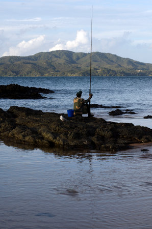 CABLE BAY,NZ-APR 22:Mature Maori man fishing from the beach on April 22 2013.New Zealand exclusive economic zone covers 4.1 million square kilometers and It's the sixth largest zone in the world.のeditorial素材