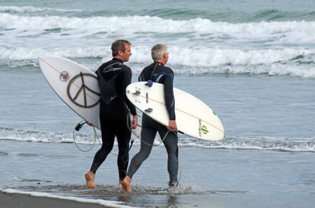 PIHA, NZ - JUNE 01:Two mature wave surfers in Piha beach near Auckland on June 01 2013.According to the International Surfing Association the estimate number of surfers worldwideのeditorial素材