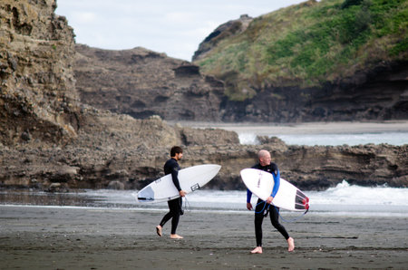 PIHA, NZ - JUNE 01:Wave surfers in Piha beach near Auckland on June 01 2013. Surfing was originated by the oceanic culture island of Polynesia and was first discovered by Captain Cook in 1778.のeditorial素材