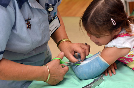 KAITAIA, NZ  - MAR 27 2014:Nurse removing an arm orthopedic cast of a child (Talya Ben-Ari age 3). Forearm fractures account for 40% to 50% of all childhood fractures.のeditorial素材