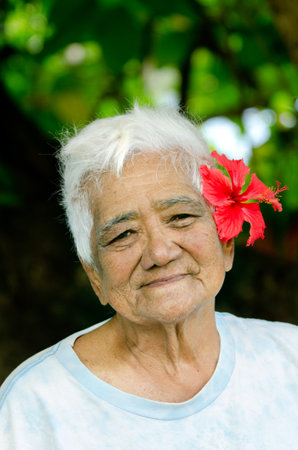 RAROTONGA - SEP 21:Exotic flower,Hibiscus , on old Cook Islander woman hair on Sep 21 2013.The Cook Islands' main population centres are on the island of Rarotonga 14,153 in 2006.のeditorial素材