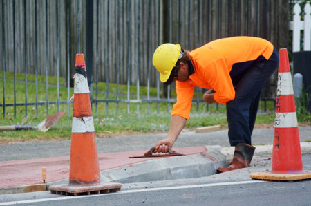 KAITAIA, NZ JAN 23:Road worker use finishing trowel tool on Jan 23 2014.The Road Maintenance crew has the responsibility for the day-to-day maintenance needs of the road system.のeditorial素材