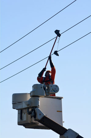 KAITIA, NZ - MAR 06:Electric engineer remove an old shoes from power line on Mar 06 2014.Shoe tossing is a common youth vandalism act of throwing a pair of shoes onto telephone wire or power lines.のeditorial素材