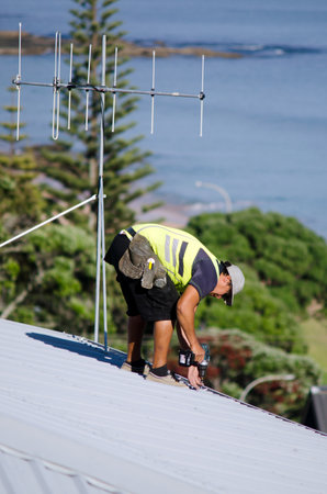 CABLE BAY,NZ:Roofer fixing a roof on Dec 12 2013. In 2000, 717 workers died of injuries caused by falls from ladders, scaffolds, buildings, or other elevations.のeditorial素材