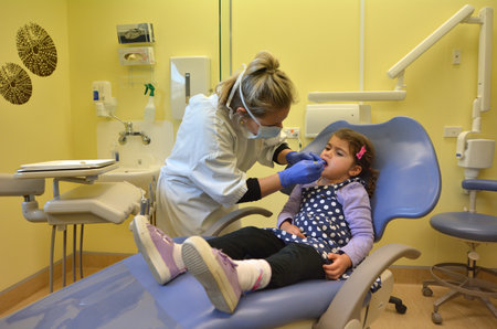 KAITAIA, NZl - JULY 14 2014: Child, little girl age 4, during the first visit to the Dentist.Humans form 2 sets of teeth over the course of their lives.Baby 20 teeth and the second set adult 32 teeth.のeditorial素材