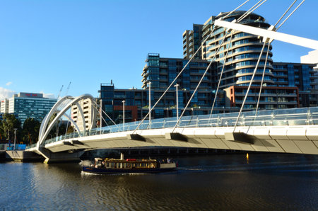 MELBOURNE,AUS - APR 14 2014:Riverboat cross under the Seafarers Bridge.It's a popular and famous footbridge over the Yarra River between Docklands and South Wharf in Melbourne, Victoria, Australia.のeditorial素材