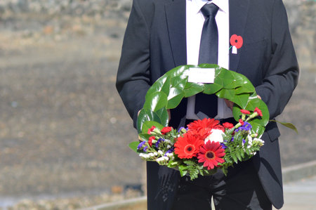 MANGONUI, NEW ZEALAND - APRIL 25 2014:New Zealander placing holds  flower wreaths during Anzac Day War Memorial Service.のeditorial素材