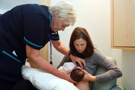 AUCKLAND - JUNE 09 2014: A Midwife help to a young mother to breastfeeding her newborn in hospital for the first time.のeditorial素材