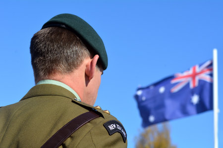 MANGONUI, NEW ZEALAND - APRIL 25 2014: New Zealand Army officer stands under New Zealand flag during the National War Memorial service.のeditorial素材