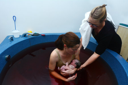 AUCKLAND - JUNE 07 2014:Woman holds her baby in a pool after natural water birth.Women have been using water in labour and birth for thousands of years.のeditorial素材