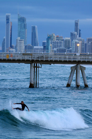 GOLD COAST - OCT 10 2014: Surfers rids a wave in the Spit beach.It is a very popular surfing beach in Surfers Paradise Gold Coast Queensland, Australia.のeditorial素材