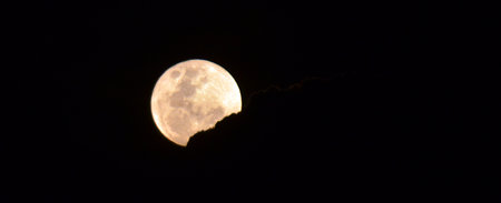 SURFERS PARADISE - NOV 05 2014:Full moon appear behind a dark cloud.It's occurs when the moon is in opposition to the Sun when the ecliptic longitudes of the Sun and Moon differ by 180 degrees.のeditorial素材