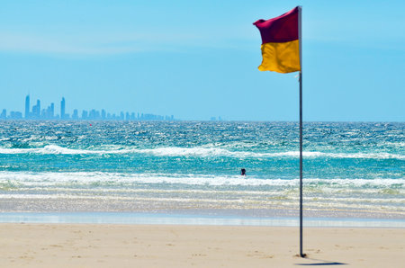 COOLANGATTA - OCT 07 2014:Australian person swim at sea beside a Lifeguards flag.According to Australia National Drowning report 300 people drown in 2012 with cost of 1 billion to the Australian economy.のeditorial素材